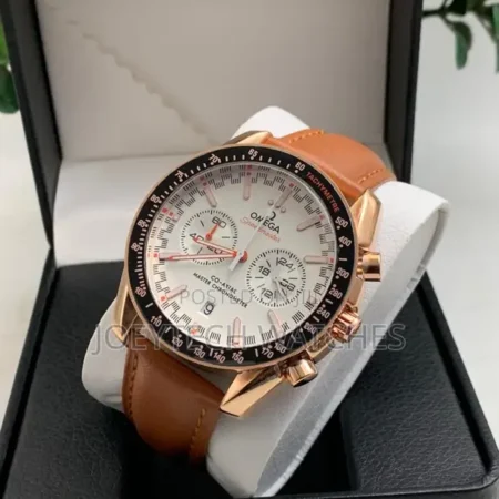 Omega Speedmaster Co-Axial Chronograph. Ce modèle particulier se distingue par son boîtier en or rose (ou alliage similaire), un cadran blanc avec des accents rouges et un bracelet en cuir marron. Cette montre est une réinterprétation de l'Omega Speedmaster, inspirée par la collaboration légendaire entre Omega et Swatch connue sous le nom de MoonSwatch